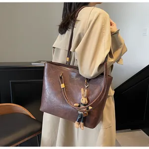 Détail du sac cabas vintage en cuir marron avec lettrage doré et pendentif lapin mignon
