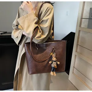 Détail du sac cabas en cuir marron foncé avec texte doré et breloque lapin en peluche