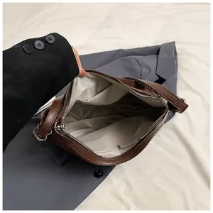Detalle del interior del bolso de cuero marrón con forro de espiga y un bolsillo con cremallera