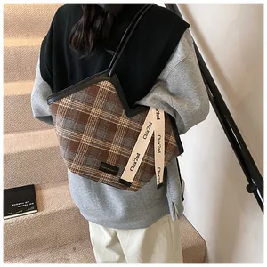Detail of plaid tote bag with crown-shaped rim and chic fabric texture on stairs