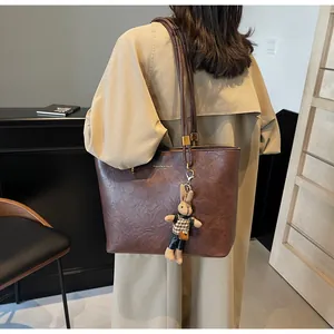 Détail du sac cabas vintage marron avec texte doré et pendentif lapin en peluche doux