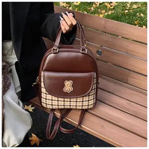 Detail of vintage patchwork backpack with plaid pocket and cute bear embroidery on wood