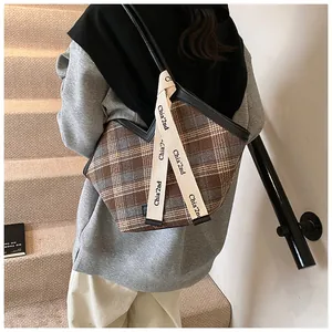 Detail of plaid canvas tote with brown checkered pattern and branded logo strap