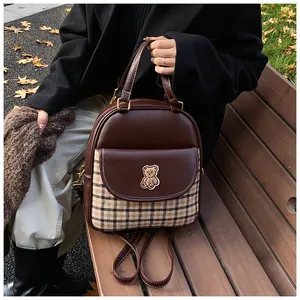 Detail of vintage brown bear backpack featuring checkered patterns on a wooden bench