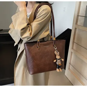 Détail du cabas en cuir marron foncé avec logo doré et pendentif lapin mignon attaché