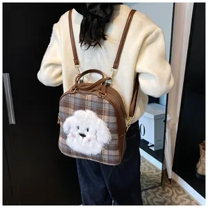 Detail of plaid tote bag with plush puppy patch and adjustable brown leather straps