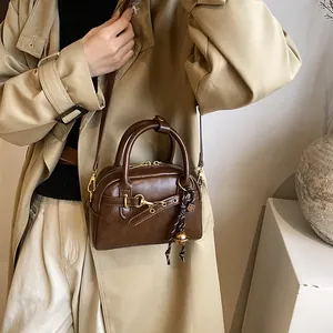 Retro brown leather mini Boston bag with metal hook and woven bell charm accessory