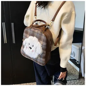 Detail of checkered small backpack featuring a plush white dog charm and leather trim