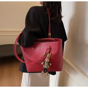 Vue détaillée du sac cabas en cuir rouge avec ferrures dorées et breloque lapin mignonne