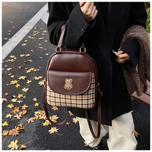Detail of brown leather and plaid backpack with bear patch and dual zip pockets