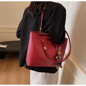 Détail du sac cabas rouge en cuir montrant le texte doré et le charm lapin pied-de-poule