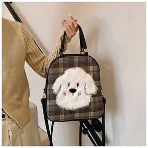 Detail of checkered tote bag featuring a cute plush dog patch and gold hardware