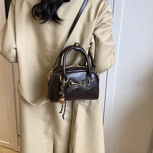 Retro deep brown leather satchel with golden hardware and adjustable strap on a trench coat