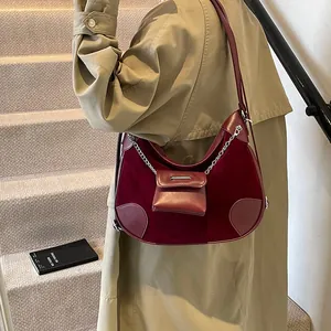 Bolso tote de media luna rojo oscuro en terciopelo con cadena de plata usado por modelo