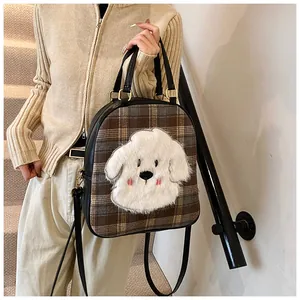 Detail of checkered tote bag with plush cartoon puppy patch and gold metal hardware