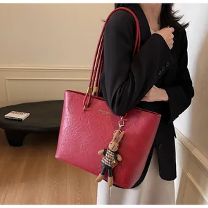 Détail d'un grand cabas rouge en cuir texturé rétro avec une breloque lapin mignonne