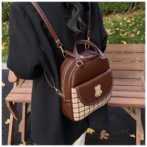 Detail of vintage brown leather backpack featuring plaid fabric trim and bear embroidery