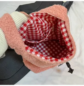 Pink plush tote bag detail showing red plaid lining and interior storage pocket
