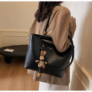 Détail du sac cabas en cuir noir avec lettrage doré et un petit pendentif lapin brun
