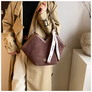 Detail of dark brown suede tote bag with V-shaped opening and white patterned silk scarf