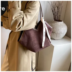 Detail of coffee brown suede tote bag featuring a V-shaped cut and stylish logo ribbon
