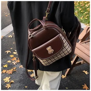Detail of a plaid backpack with bear embroidery on a scenic autumn street background