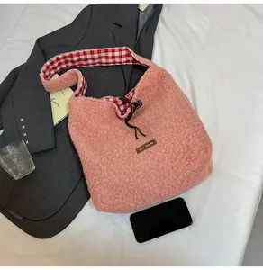 Close-up of pink faux shearling bucket bag with drawstring closure and brand patch
