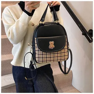 Detail of a mini plaid patchwork backpack with golden bear embroidery and leather straps