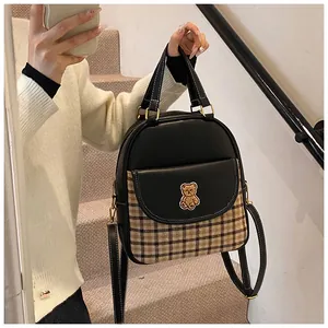 Detail of small color-block backpack with classic plaid fabric and bear patch