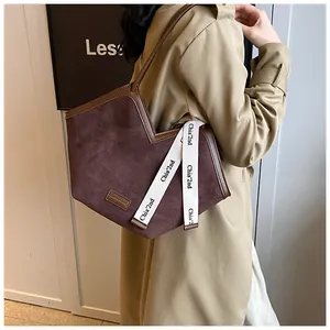 Detail of fabric tote bag with brown suede texture and V-shaped opening on a model