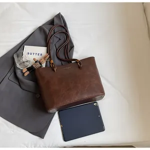 Détail du sac cabas en cuir marron vintage avec pendentif lapin et tablette de mesure