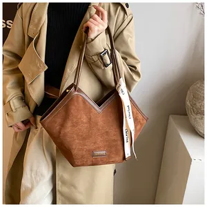 Detailed shot of brown suede tote bag with V-shaped leather trim and decorative scarf
