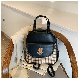 Detail of checkered patchwork backpack with cute bear embroidery on a wooden chair