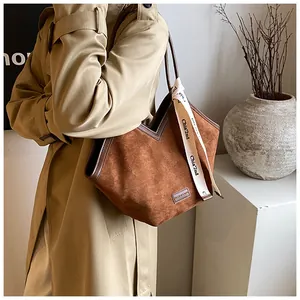 Detail of dark brown suede tote bag featuring V-cut opening and branded silk ribbon