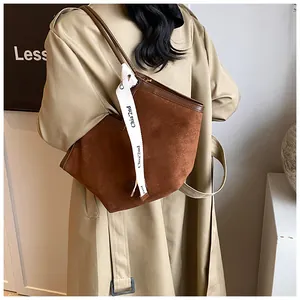 Detail of brown suede tote bag with leather trim and decorative silk ribbon