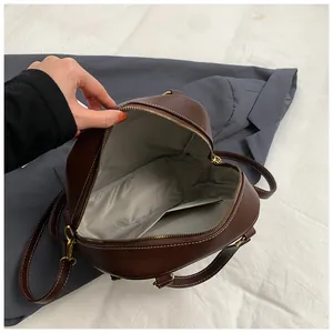 Macro view of brown leather backpack interior with gray fabric lining and inner pocket