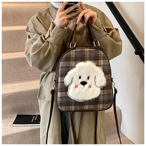 Close-up of brown plaid tote bag featuring a plush white puppy decor and leather handle