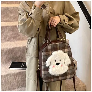 Close-up of brown plaid tote bag featuring a cute plush puppy patch and gold metal hardware