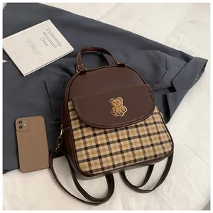 Detail of vintage brown plaid backpack with cute bear embroidery on textured PU leather