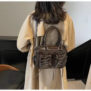 Detail of dark brown glossy patent leather crossbody bag with small bow pockets on back