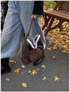 Detailed view of a brown suede tote bag featuring white faux fur trim and horn buckle buttons