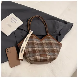 Detail of vintage plaid tote bag with brown leather trim and retro canvas textures