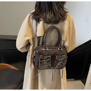 Detail of dark brown glossy bag with bow pockets and contrast stitching on a coat