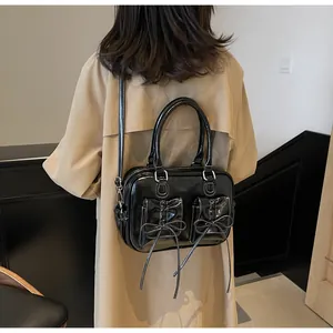 Detail of black glossy shoulder bag with bow pockets and white contrast stitching