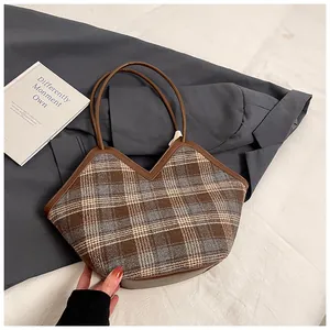 Detailed view of the plaid fabric texture and brown leather trim on the tote bag