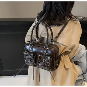 Detail of dark brown glossy patent leather bag with bow pockets and white stitching