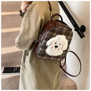 Detailed view of brown plaid backpack featuring a cute 3D plush puppy patch and leather straps