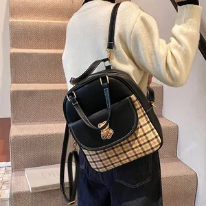 Fashionable black leather backpack with brown check pocket and gold bear detail on stairs