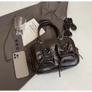 Detail of dark brown glossy underarm bag featuring bow pockets and contrast stitching