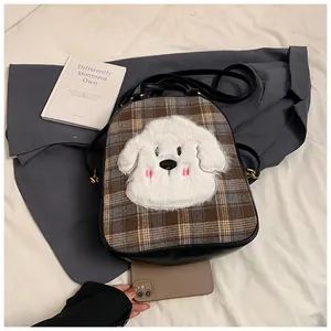 Macro shot of plaid tote bag featuring a cute plush dog patch and golden zipper details